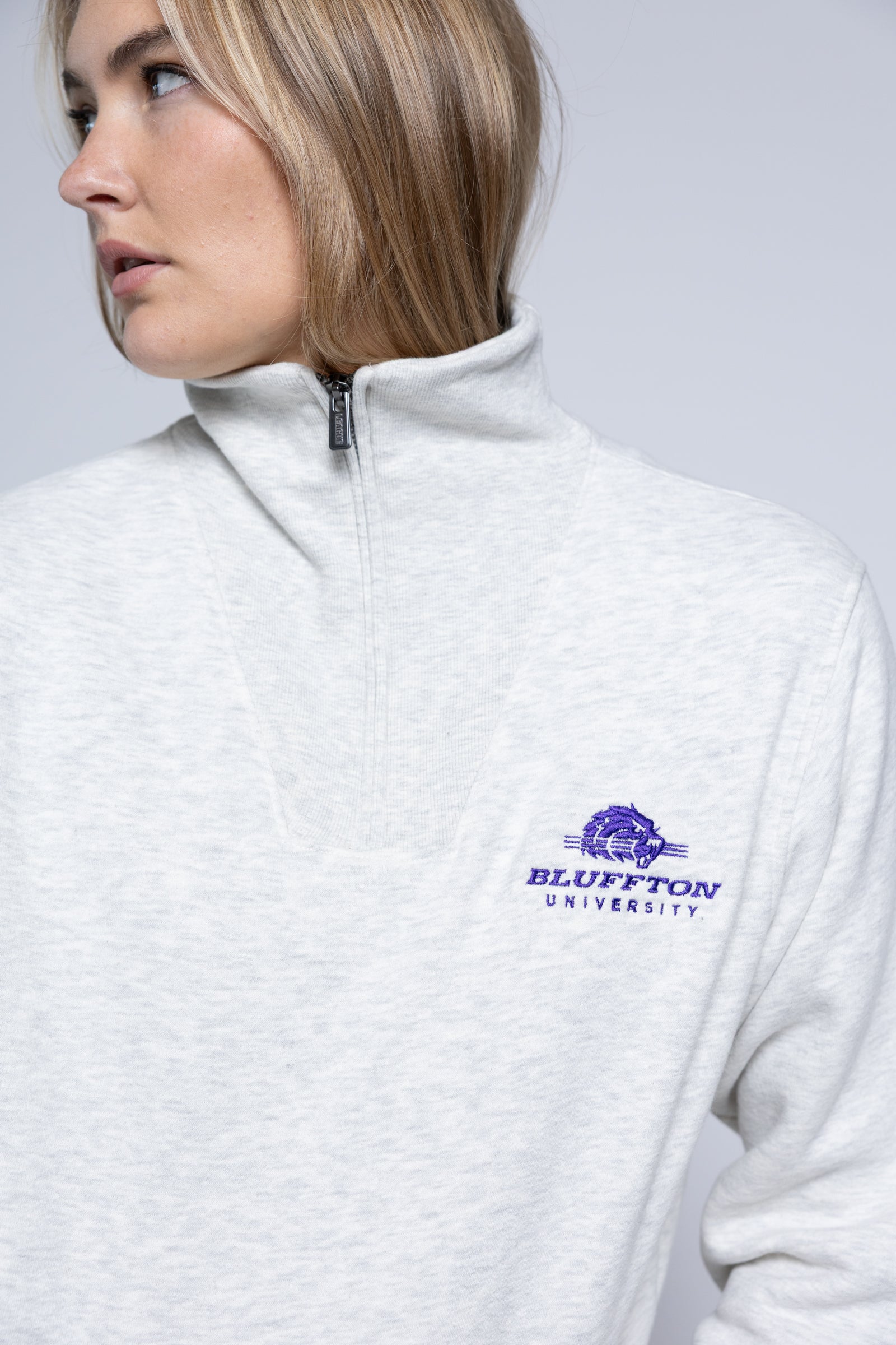 Person wearing a white jacket with 'Bluffton University' logo on a gray background