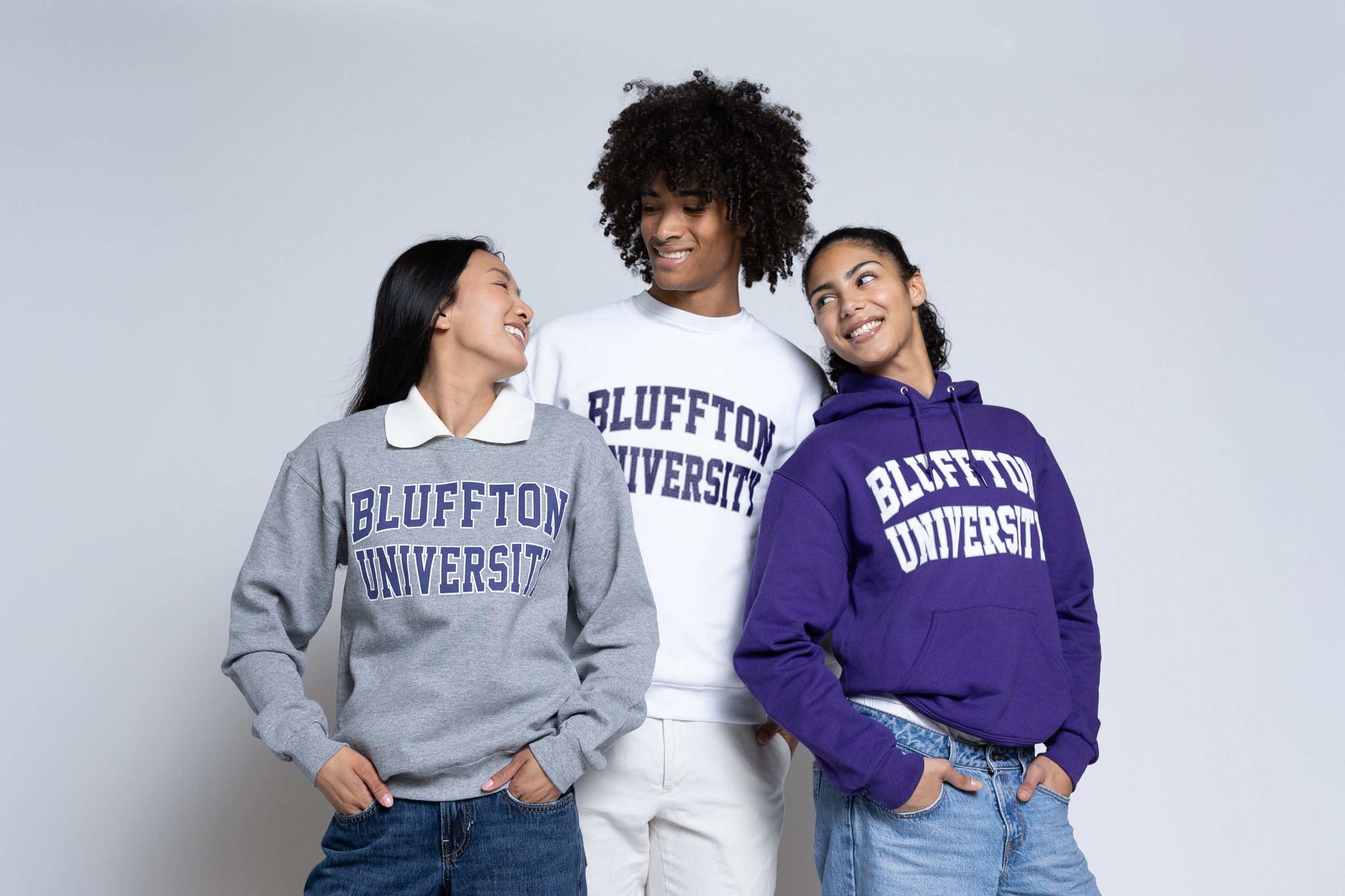 Three people wearing Bluffton University sweatshirts against a plain background