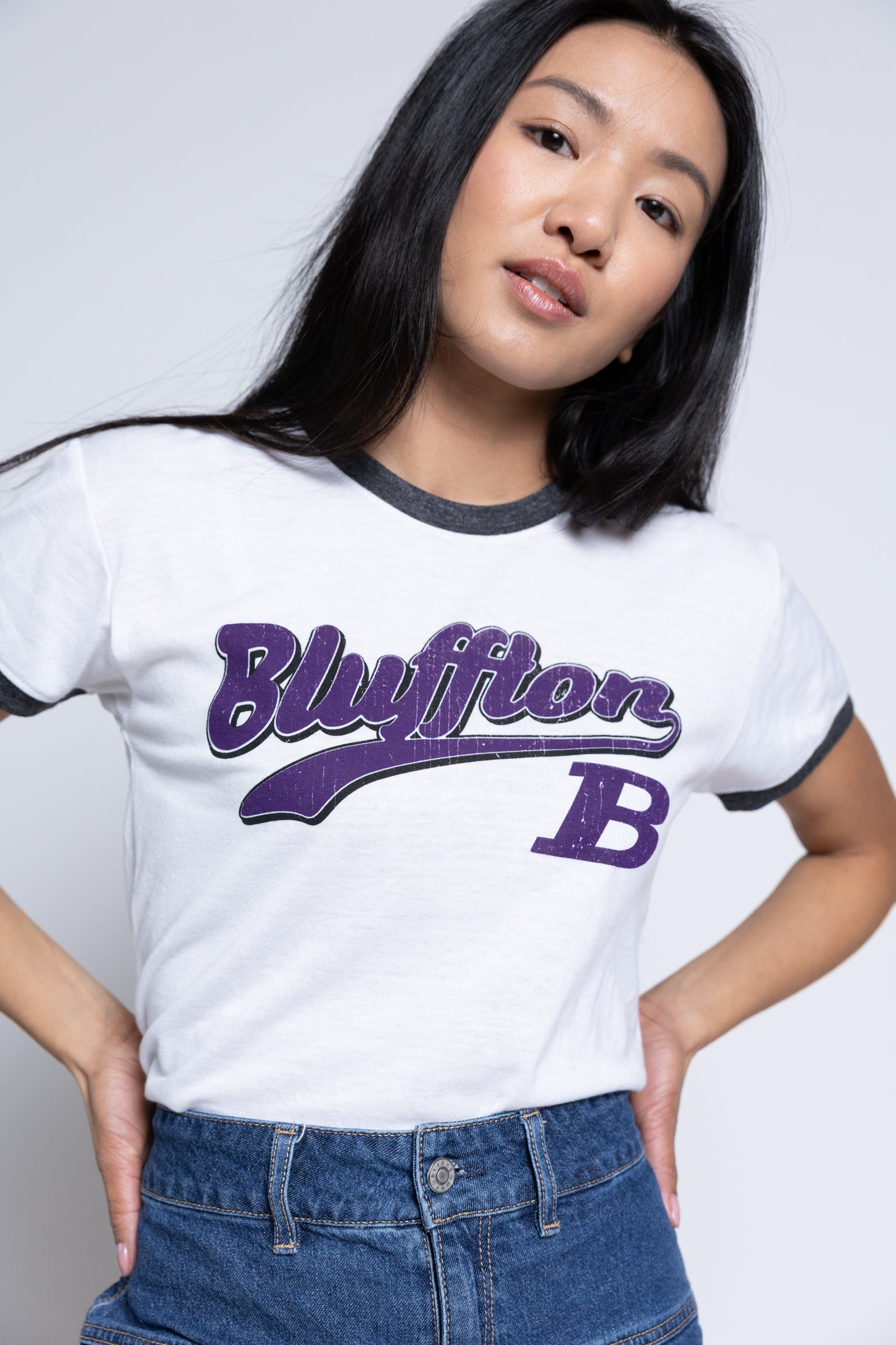 Person wearing a white t-shirt with 'Bluffton B' printed in purple on a plain background